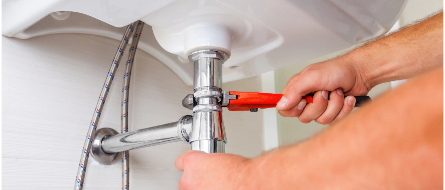 plumber hands close up with wrench tool repairing bathroom pipes